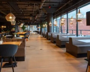 Modern restaurantinterieur in Groningen met houten vloer, grijze zitbanken en stijlvolle hanglampen.