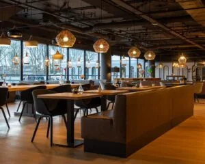 Modern ingerichte horecaruimte in Groningen met houten vloeren, stijlvolle verlichting en grote ramen met uitzicht op de straat.