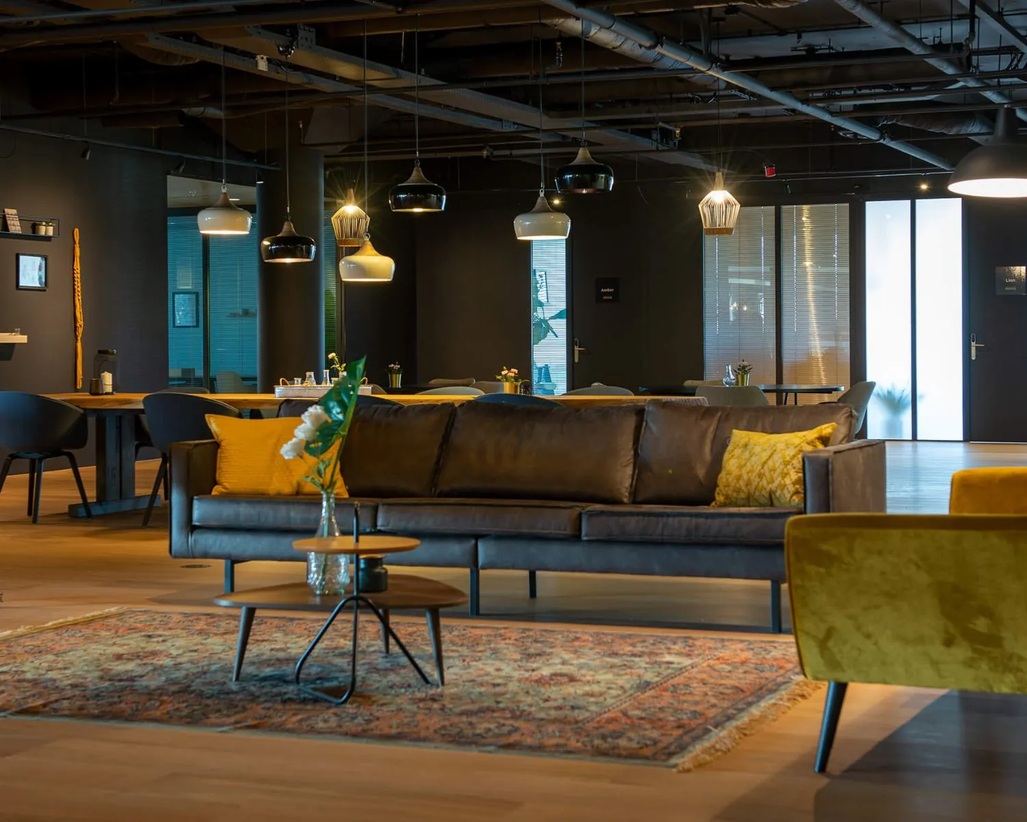 Moderne lounge in Groningen met een leren bank, kleurrijke kussens, designverlichting en een sfeervol interieur.