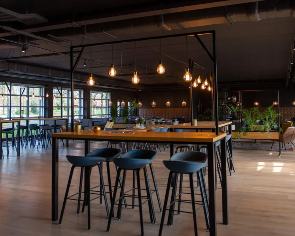 Modern ingerichte horecaruimte in het Stadspark in Groningen met hoge tafels, barkrukken en warme sfeerverlichting.
