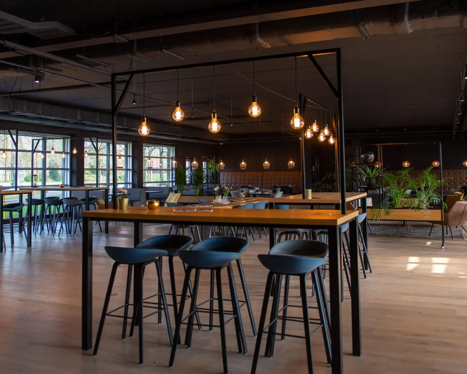 Modern ingerichte horecaruimte in het Stadspark in Groningen met hoge tafels, barkrukken en warme sfeerverlichting.