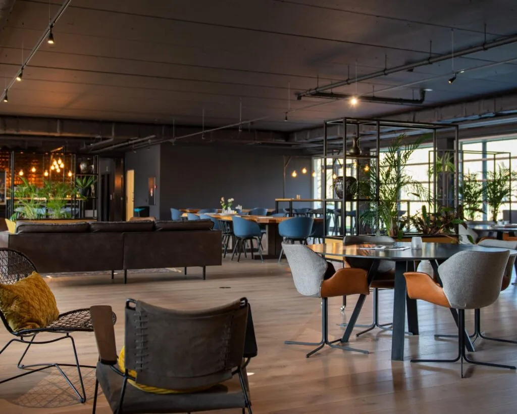 Modern ingericht interieur van een lounge- en werkruimte in het Stadspark van Groningen met comfortabele zitplekken en veel groen.