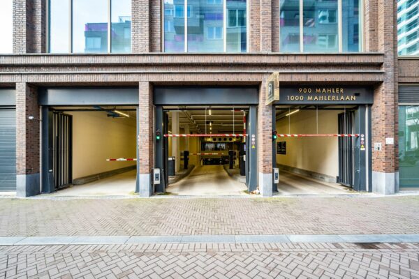 Entree van een ondergrondse parkeergarage aan de Gustav Mahlerlaan 900-1000 met slagbomen en open garagepoorten.