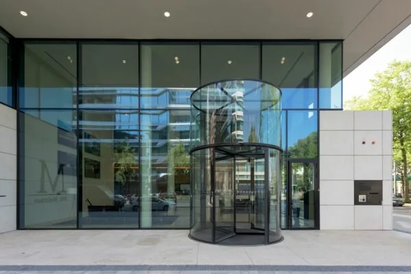 Ingang met glazen draaideur en grote ramen van het kantoorgebouw aan de Gustav Mahlerlaan 1025 in Amsterdam.