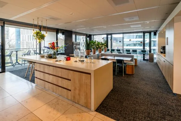 Moderne bedrijfskeuken en lunchruimte op Gustav Mahlerlaan 1025 met uitzicht op kantoorgebouwen.
