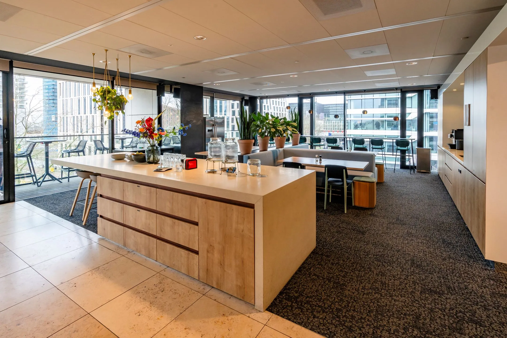 Moderne bedrijfskeuken en lunchruimte op Gustav Mahlerlaan 1025 met uitzicht op kantoorgebouwen.