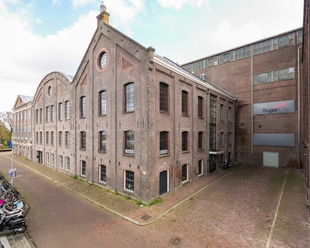 Voormalige suikerfabriek aan de Haarlemmerstraatweg 11 in Halfweg, nu in gebruik als SugarCity, met karakteristieke bakstenen gevels en industriële ramen.