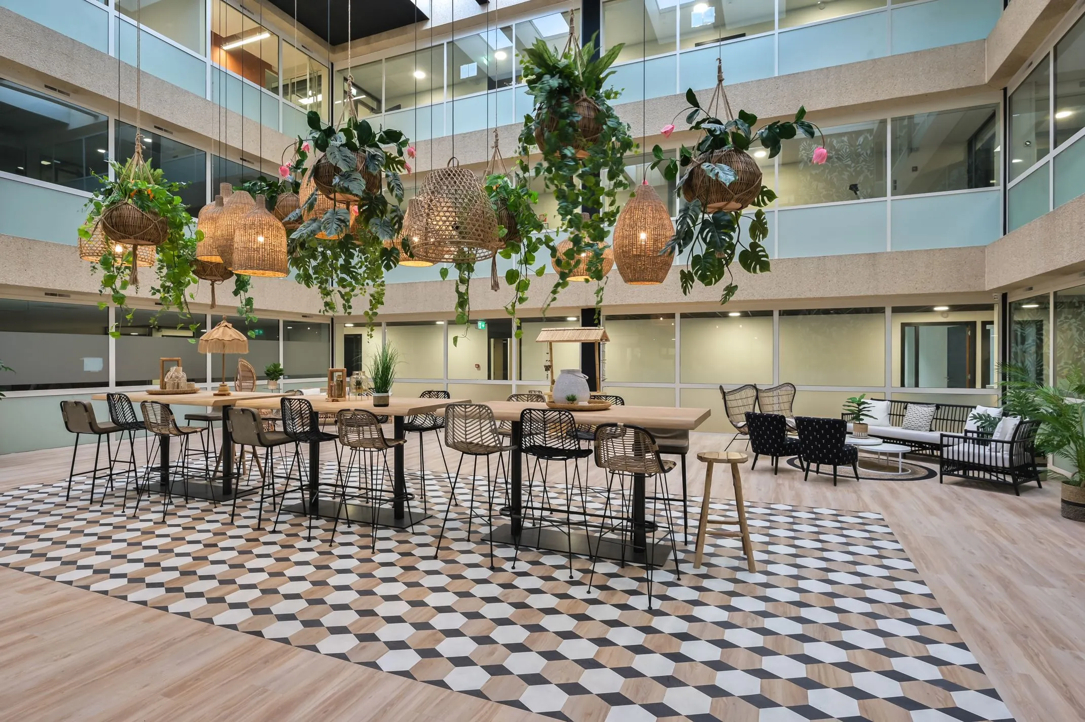 Moderne kantoorruimte aan de Havenweg 24 met een grote houten tafel, hangende planten, rotanlampen en een zithoek.