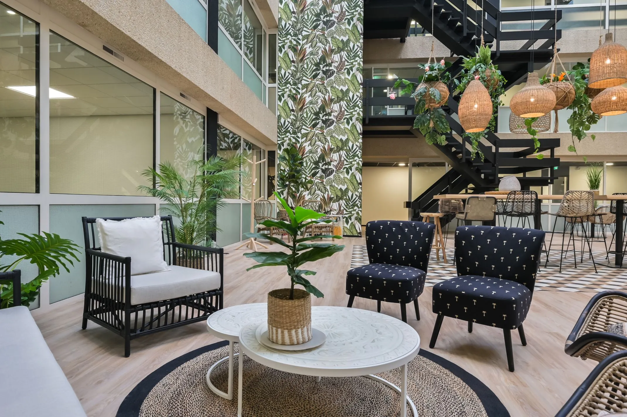 Stijlvol ingerichte wachtruimte in Havenweg 24 met planten, rotan lampen en moderne zitmeubels.