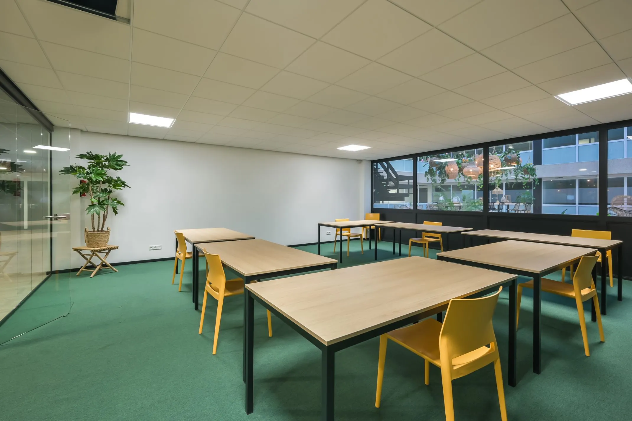 Moderne vergaderruimte aan de Havenweg 24 met houten tafels, gele stoelen en een glazen wand.