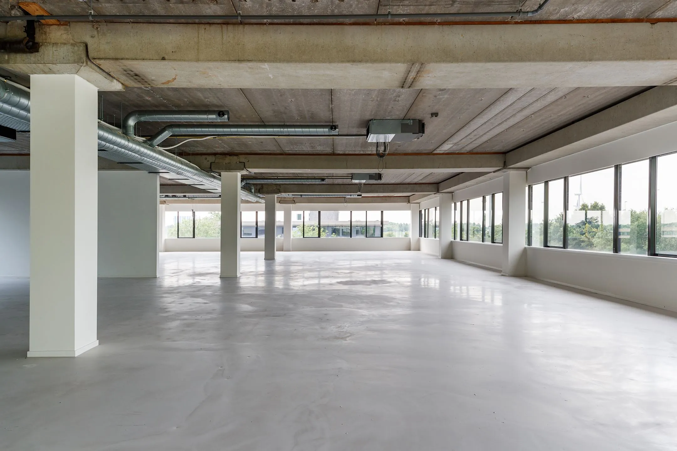 Lichte, ruime kantoorruimte aan de Havenweg 24 met betonnen plafond en grote raampartijen.