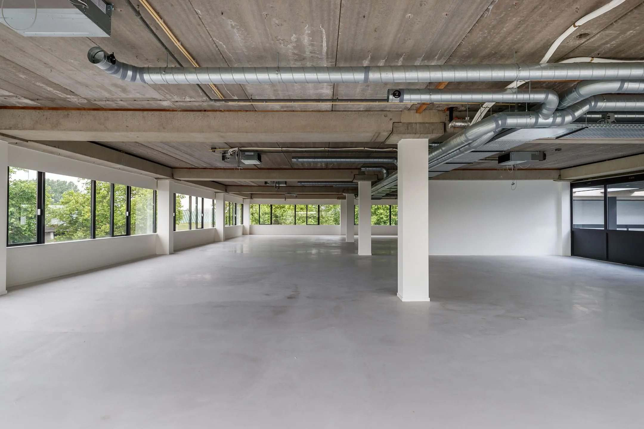 Leeg industrieel kantoorruimte aan de Havenweg 24 met zichtbare ventilatiebuizen en grote ramen.