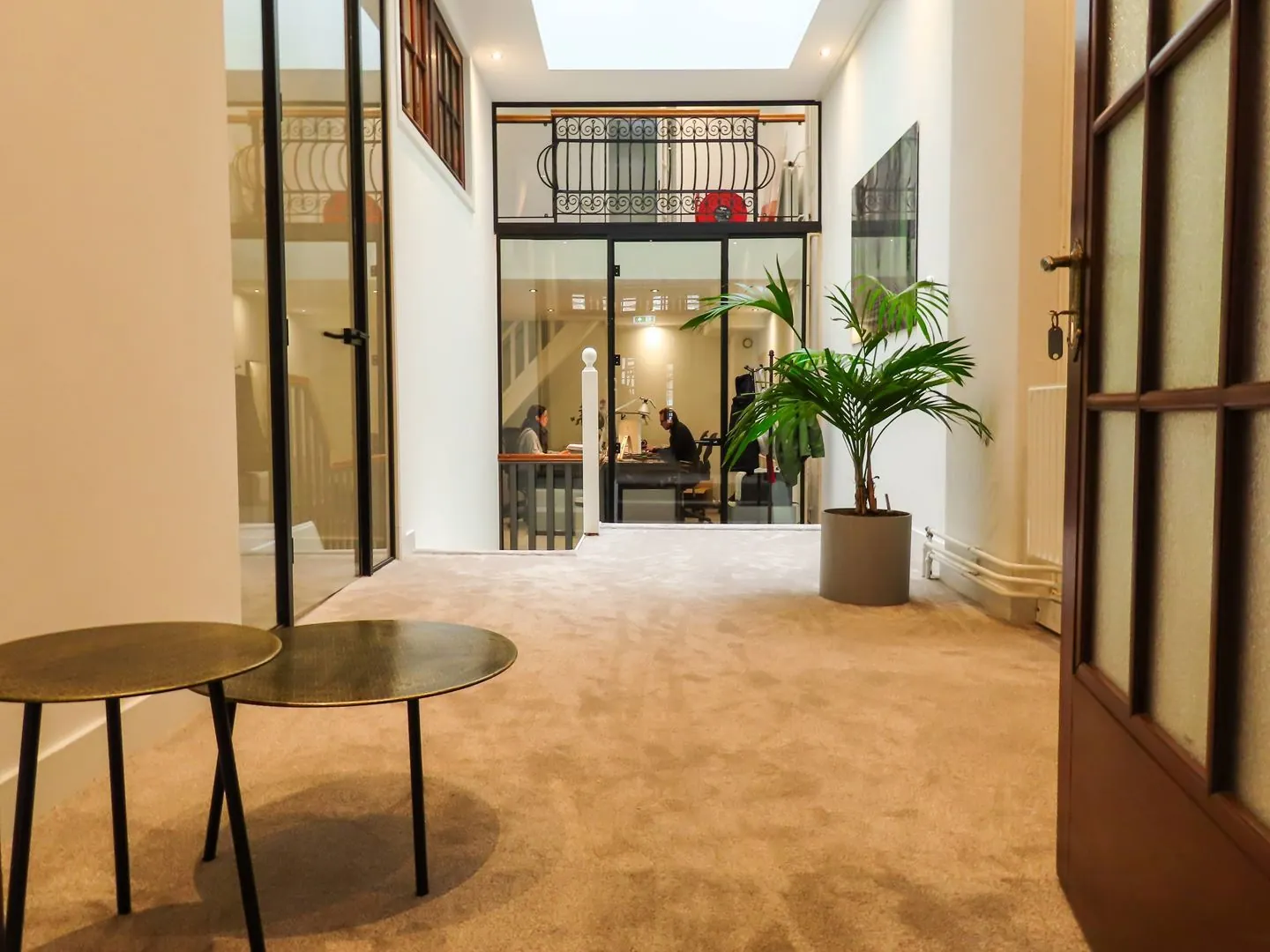 Moderne kantoorruimte aan de Herengracht 449 met glazen wanden, een plant in een pot en zicht op een vergaderruimte.