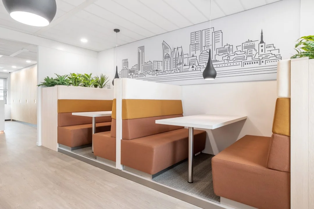 Moderne kantoorzitjes met bruin-oranje bekleding en een muurtekening van de skyline, ingericht in Hoogstraat 1001.