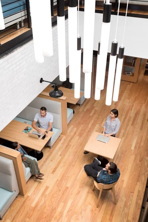 Vier mensen werken en overleggen aan houten tafels in een moderne, lichte ruimte aan de Hoogstraat 1001.