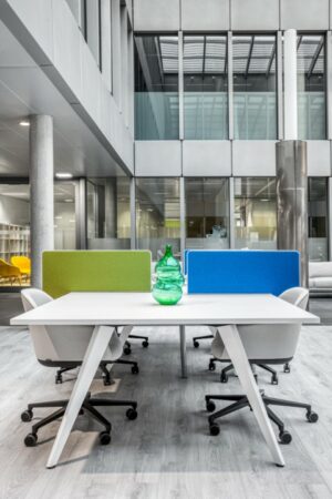 Moderne vergadertafel met zes bureaustoelen, kleurrijke schermen en een groene vaas in een licht kantoorinterieur aan de Hoogstraat 1001.