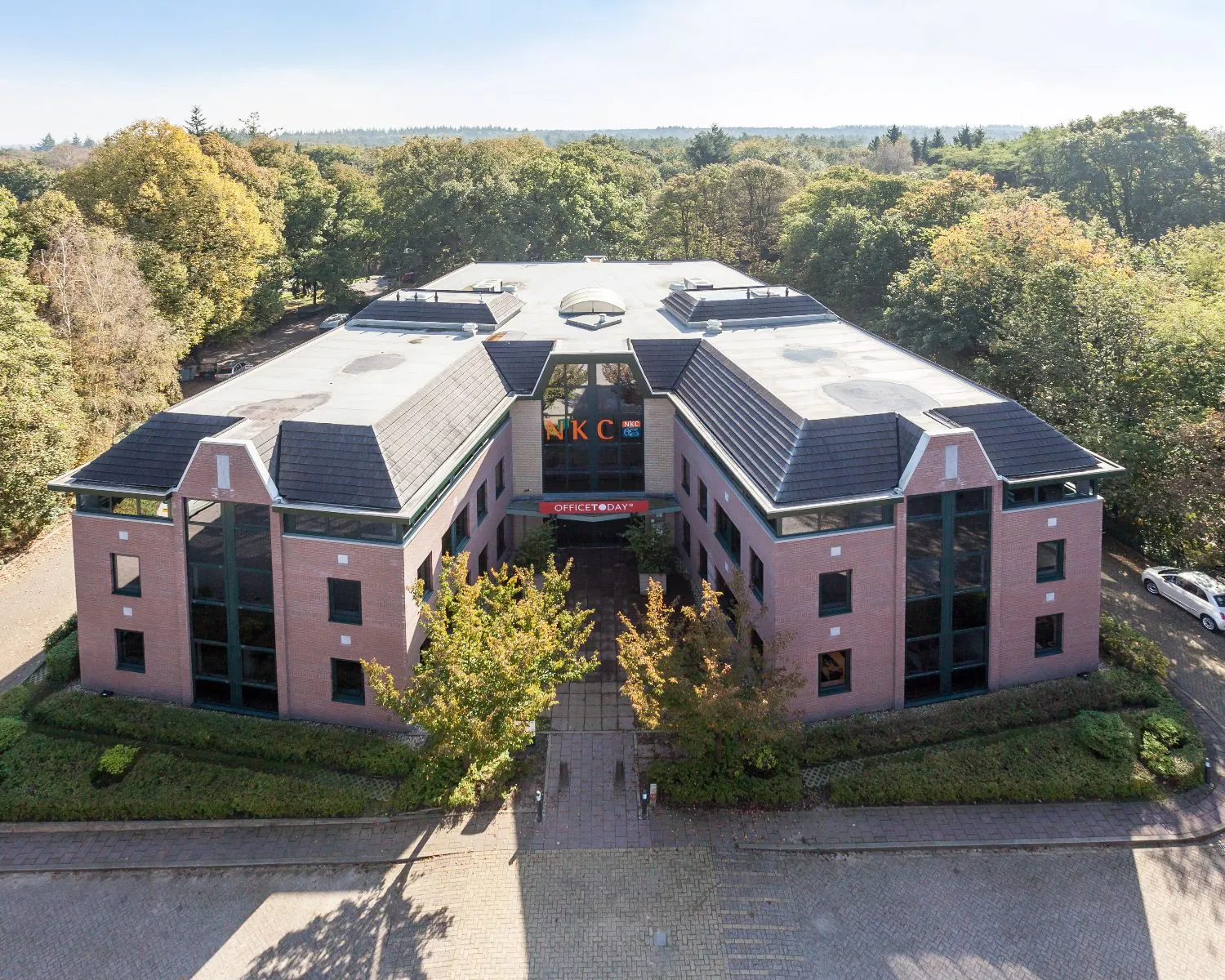 Luchtfoto van het kantoorgebouw van NKC aan de rand van een bosrijk gebied.