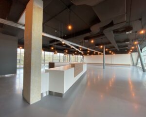 Moderne, lege kantoorruimte met een centraal wit-walnoothouten kookeiland en industriële verlichting.