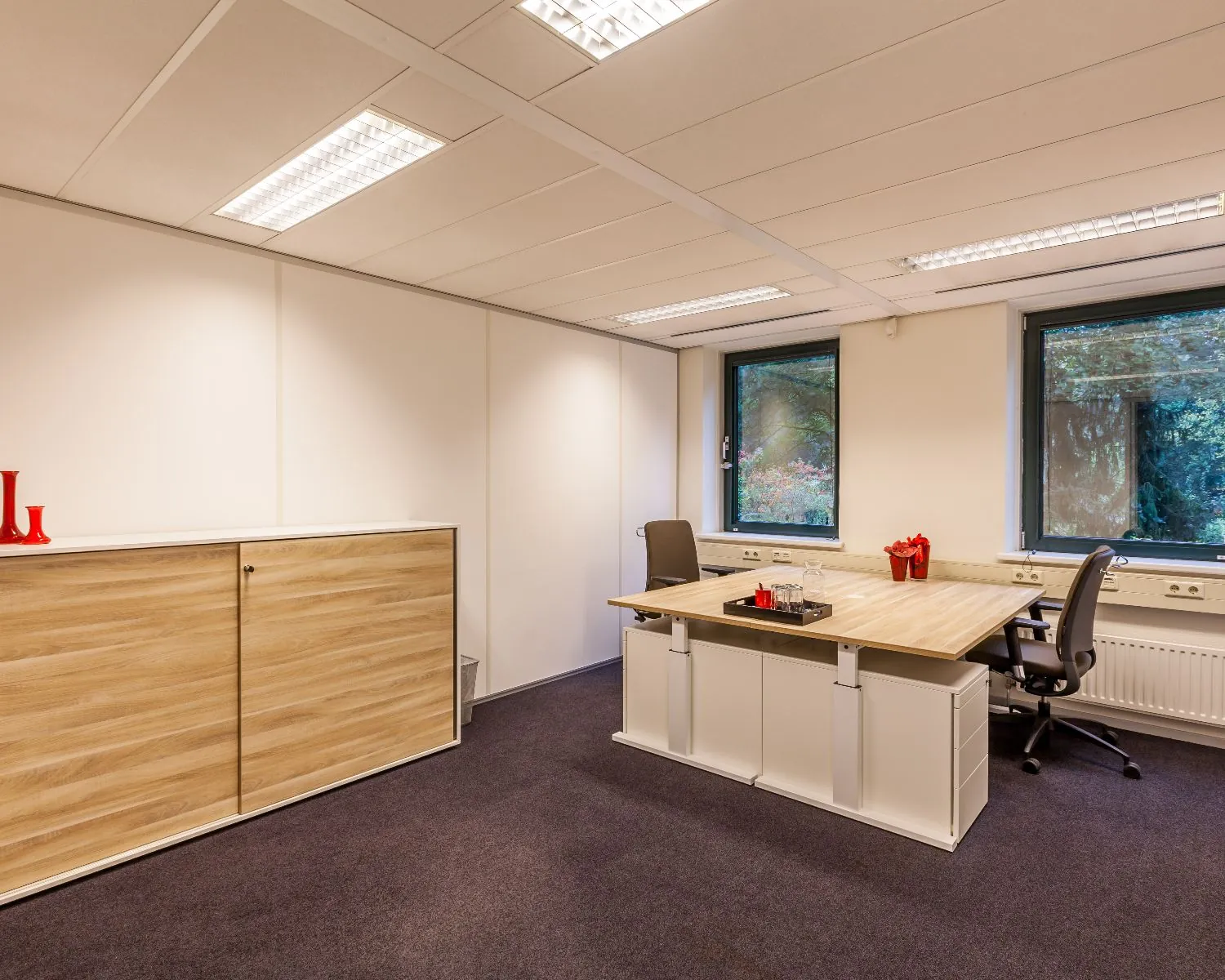 Modern en netjes ingericht kantoor met twee bureaustoelen, een houten bureau en een opbergkast.