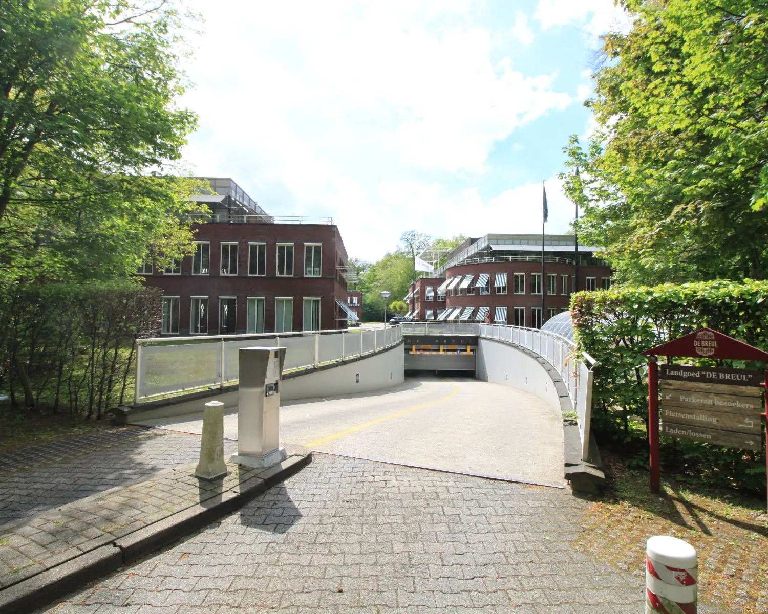 Ingang naar de parkeergarage van Landgoed De Breul met op de achtergrond rode bakstenen kantoorgebouwen.