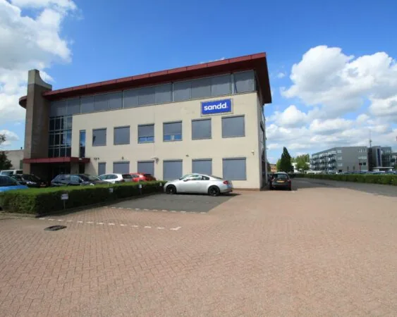 Kantoorgebouw van Sandd met parkeergelegenheid op een zonnige dag.