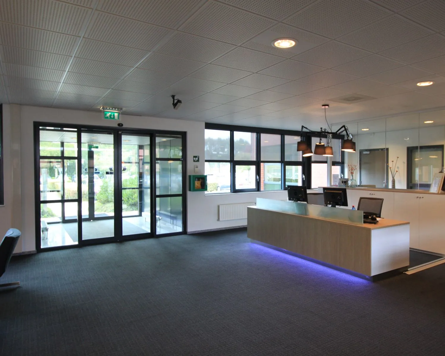 Moderne receptieruimte met een balie, computers en sfeerverlichting, gelegen bij een glazen entree.