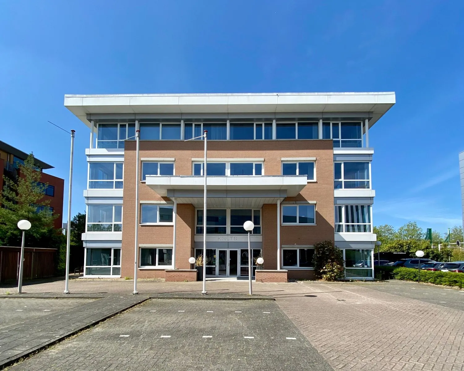 Vooraanzicht van het kantoorgebouw KNTTB op een zonnige dag.