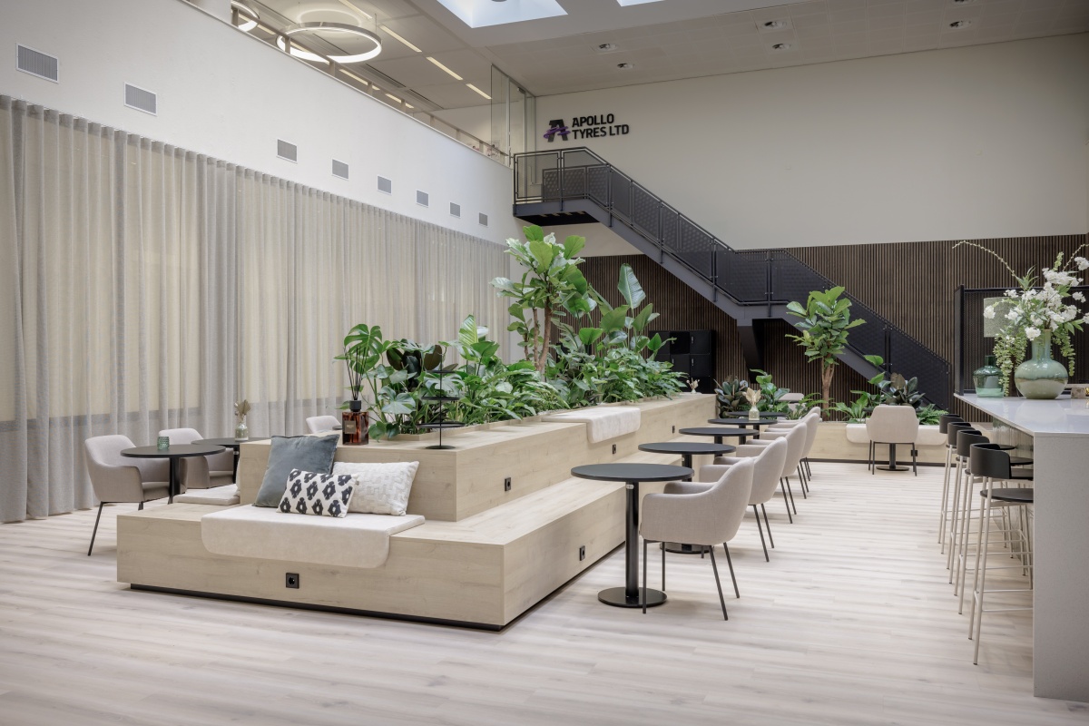 Een moderne kantoorruimte met planten, zitgelegenheid en het logo van Apollo Tyres Ltd.