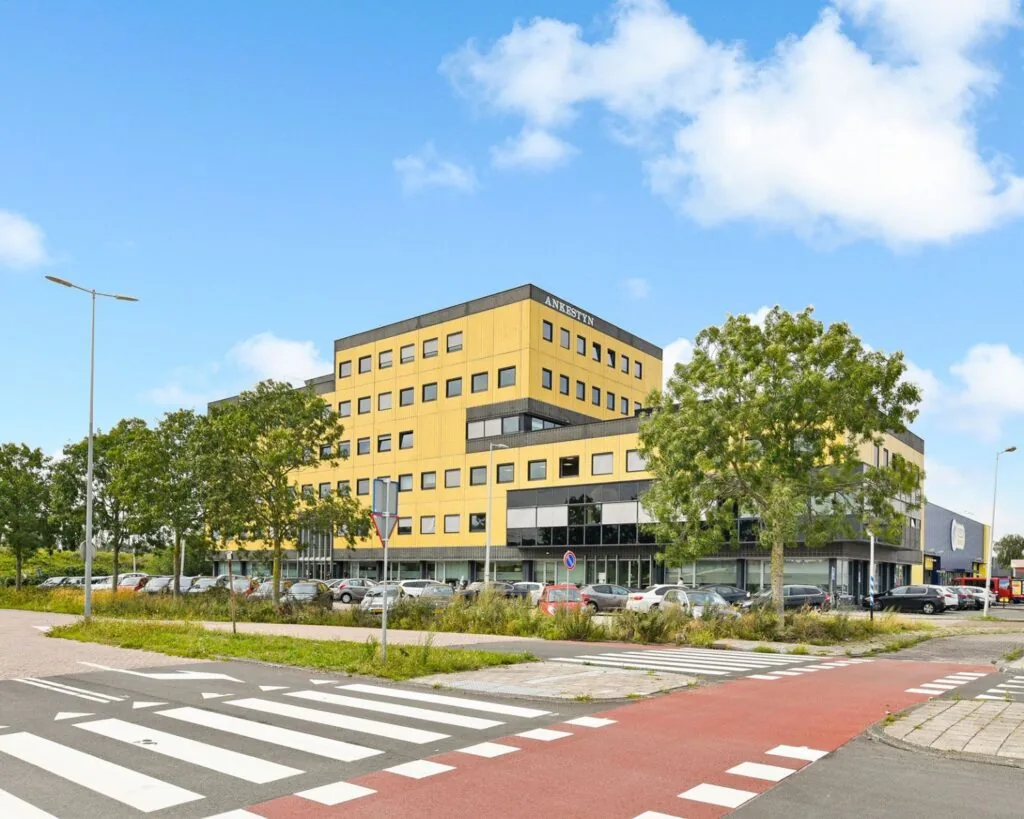 Kantoorgebouw aan de Joan Muyskenweg 40-146 in Amsterdam met gele gevel en omliggende parkeerplaats.