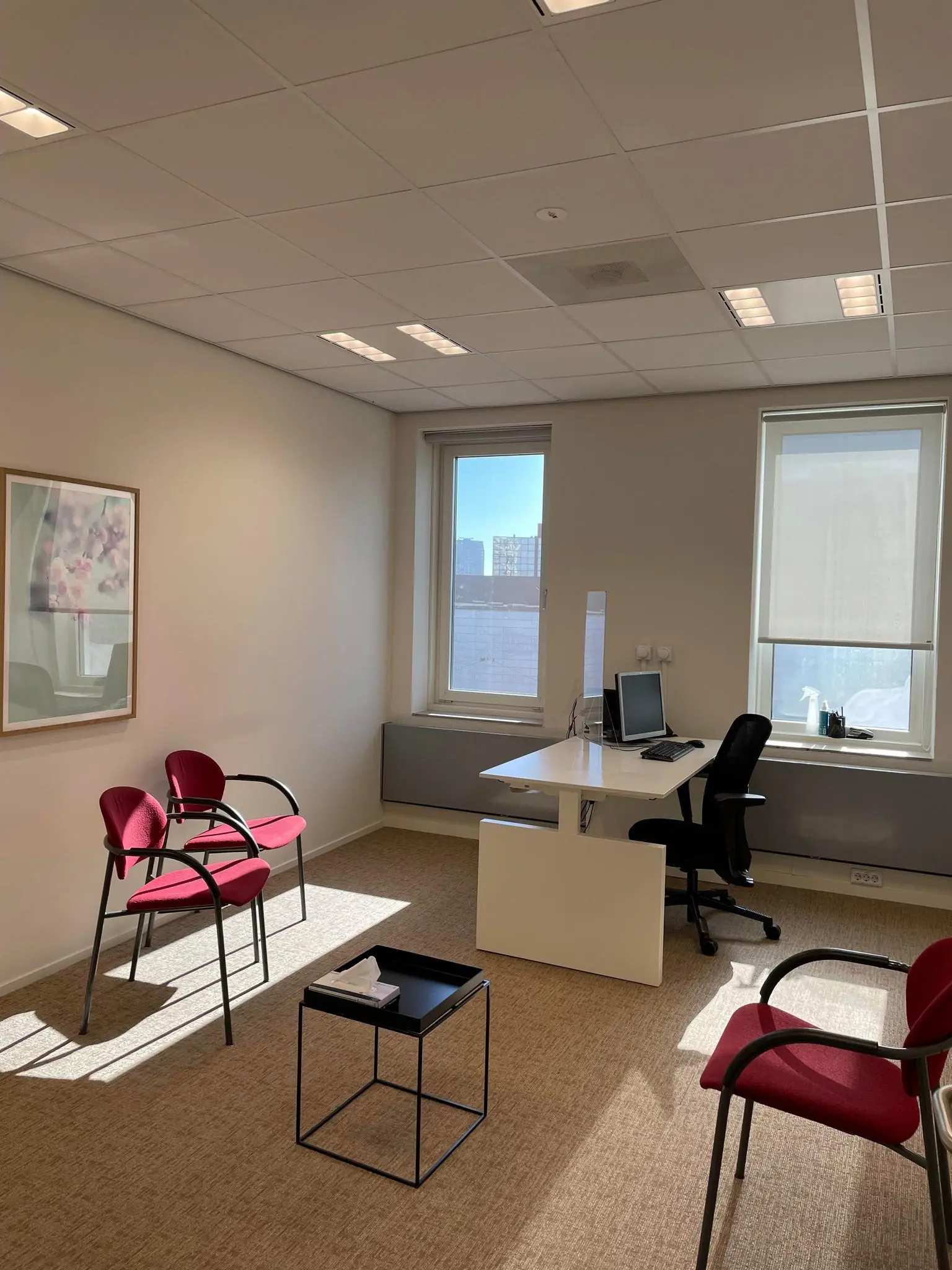 Licht en modern ingericht kantoor aan de Johan Cruijff Boulevard met bureaumeubel, bezoekersstoelen en groot raam.