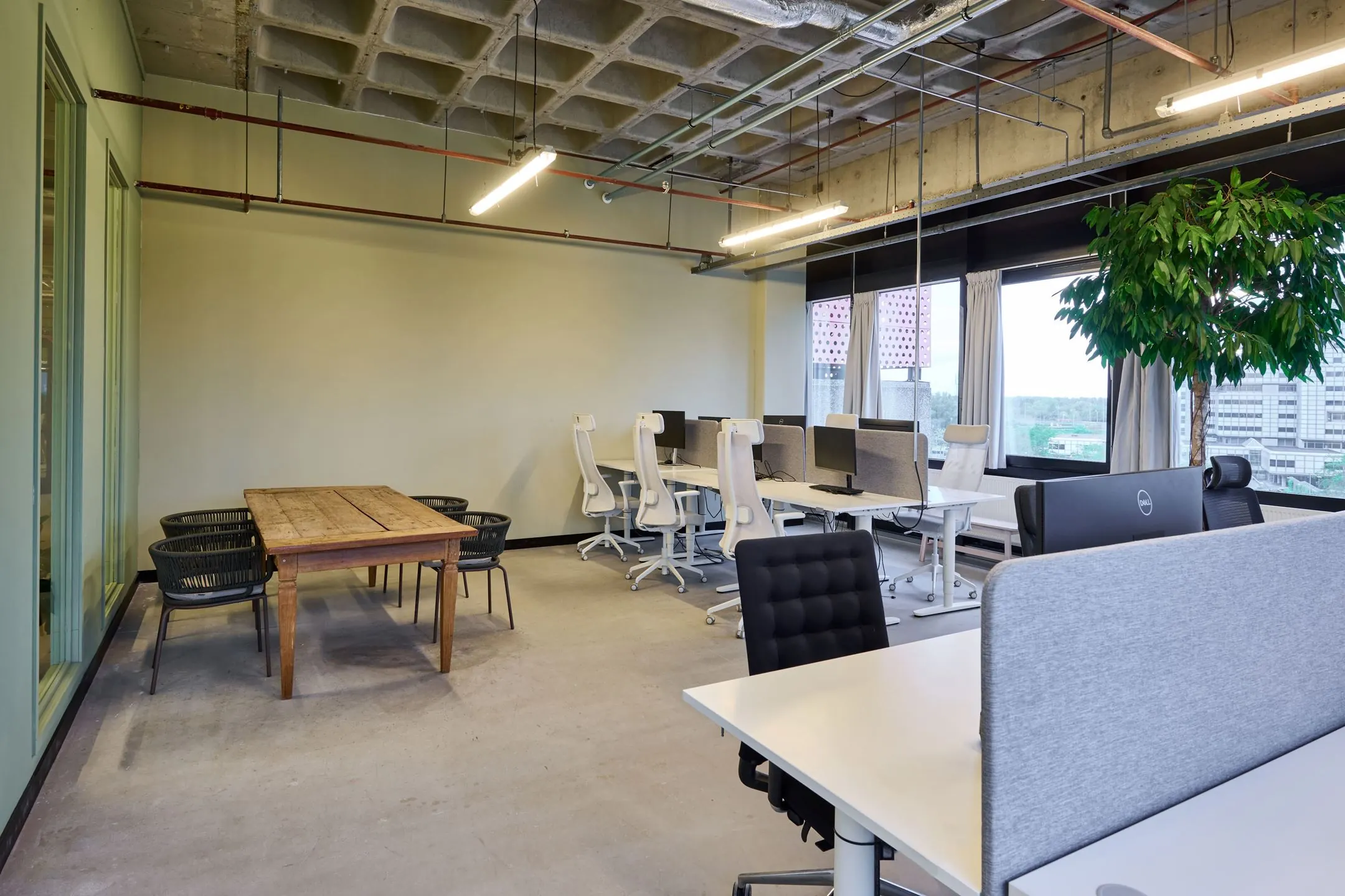 Modern kantoorinterieur aan de Johan Huizingalaan 763a met werkplekken, houten vergadertafel en grote raampartijen.