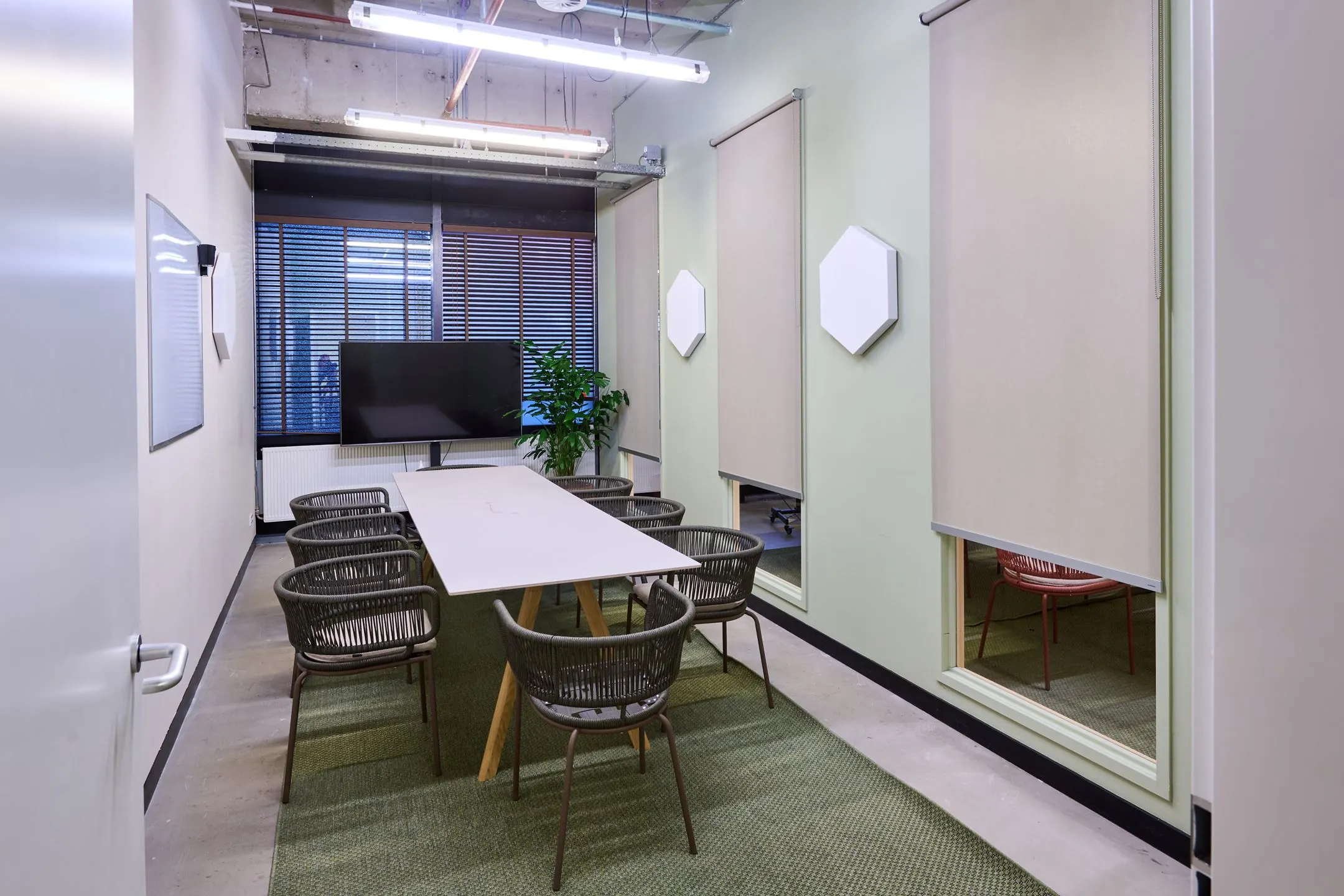 Vergaderruimte aan de Johan Huizingalaan 763a met moderne inrichting, een lange tafel, acht stoelen en een flatscreen-tv.