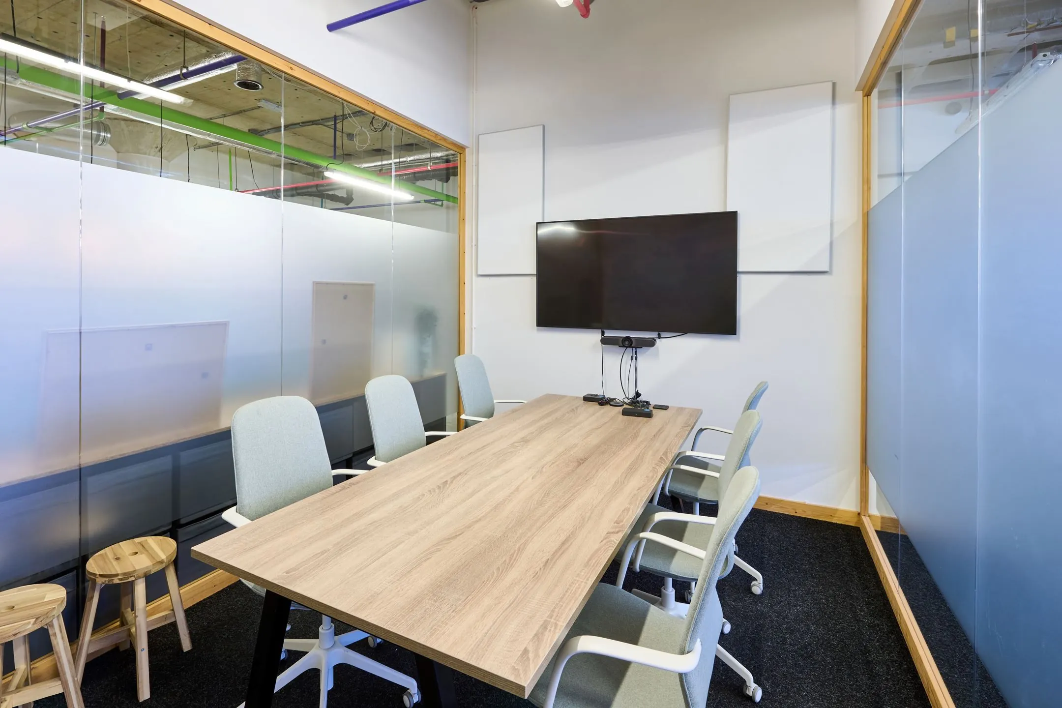 Vergaderruimte met een houten tafel, zes stoelen, een flatscreen en glazen wanden aan de Johan Huizingalaan 763a.