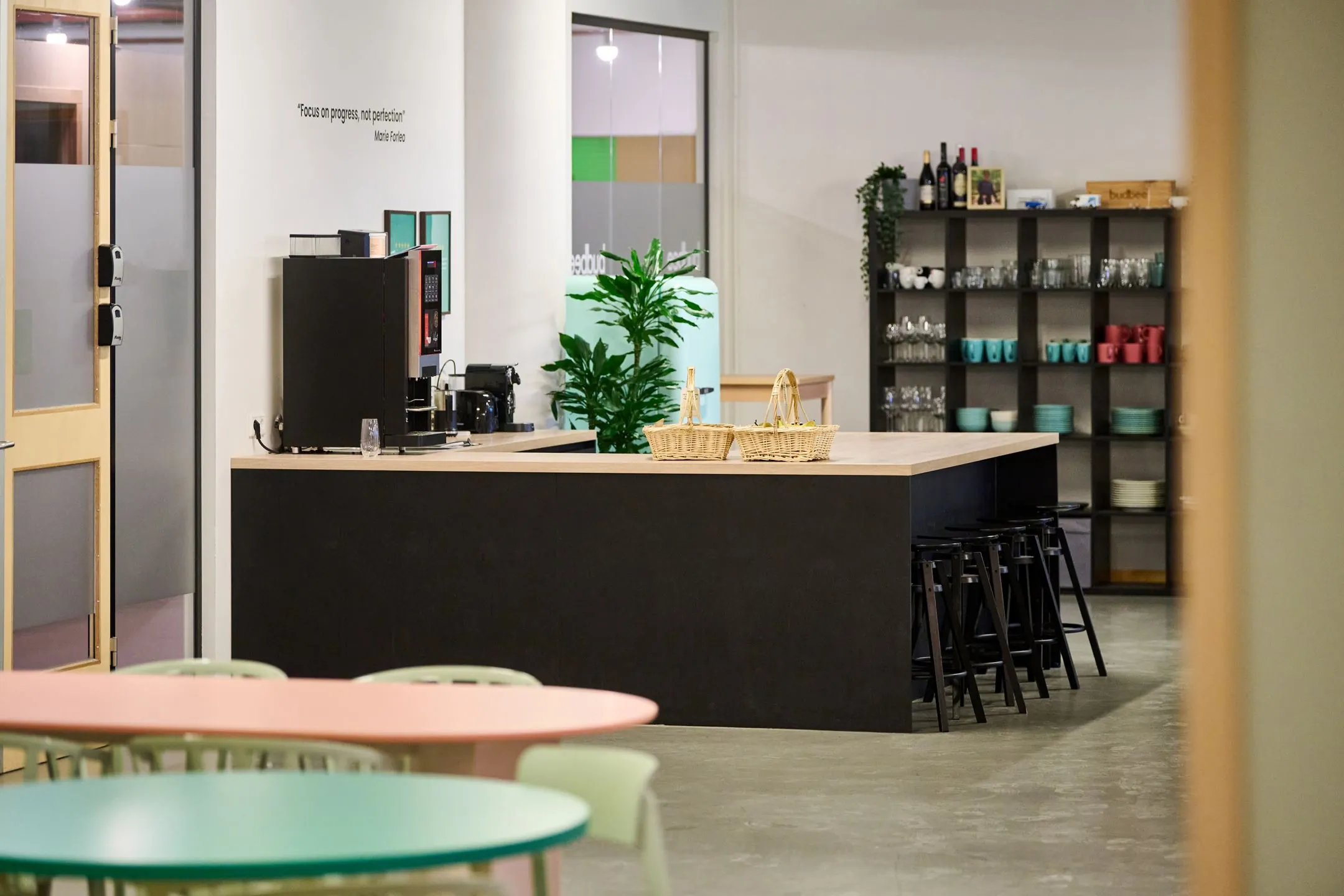 Moderne pantryruimte in een kantoor aan de Johan Huizingalaan 763a met koffieapparaat, bar, zitplaatsen en een open keukenkast met servies.