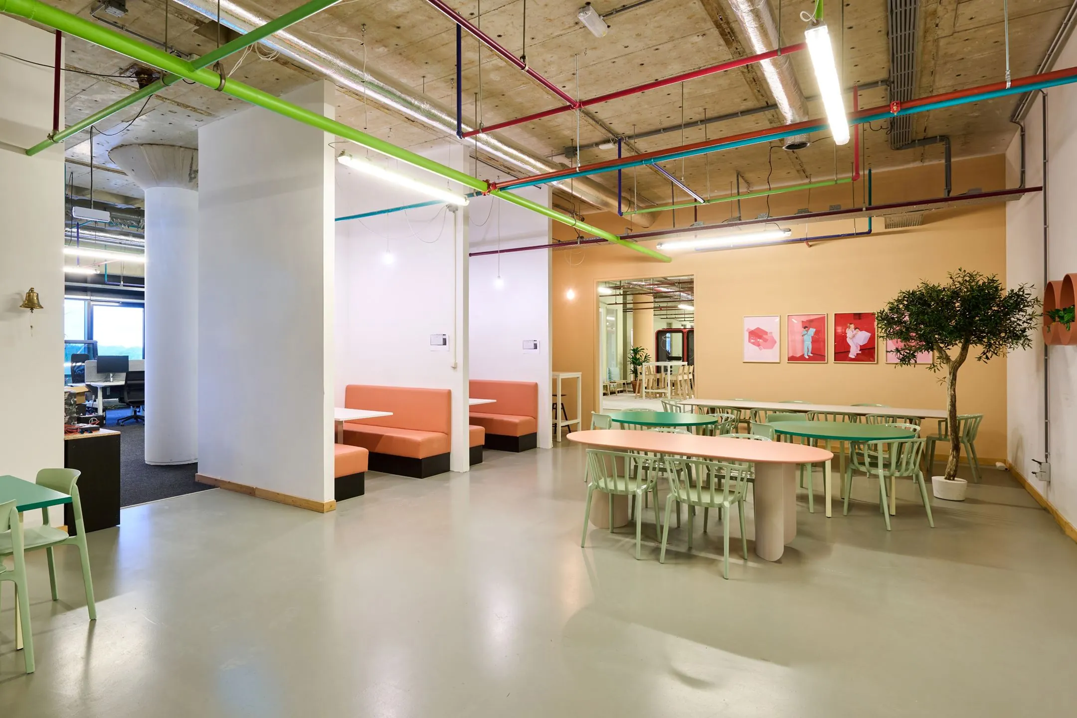 Moderne, kleurrijke kantine met mintgroene stoelen, perzikkleurige banken en industriële plafondleidingen aan de Johan Huizingalaan 763a.