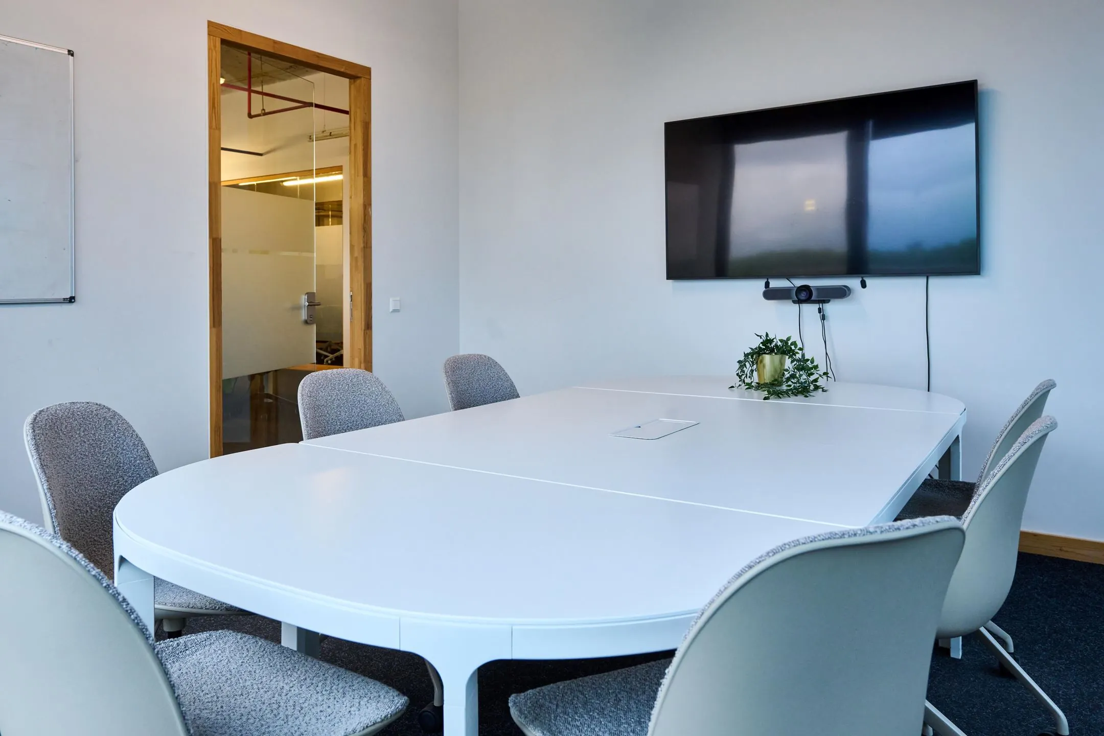 Vergaderkamer aan de Johan Huizingalaan 763a met ovale tafel, stoelen, groot beeldscherm en videoconferentieapparatuur.