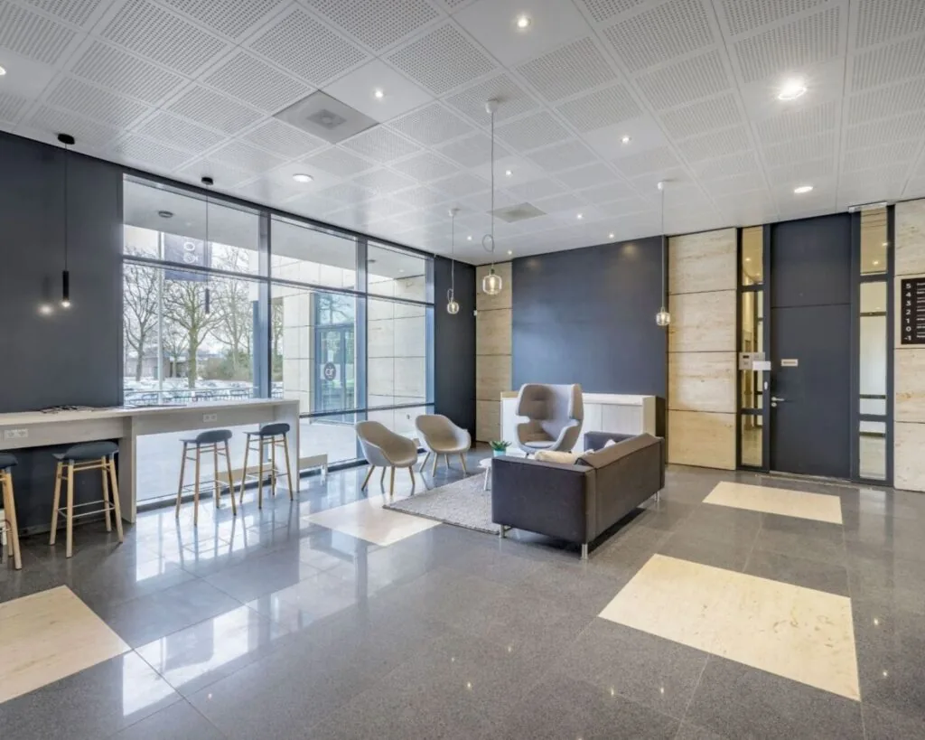 Moderne ontvangstruimte met zithoek en hoge ramen in een kantoorgebouw aan de Anderlechtstraat 15.