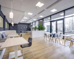 Moderne kantoorlounge met veel daglicht, houten vloer en zitgelegenheid aan de Anderlechtstraat 15.