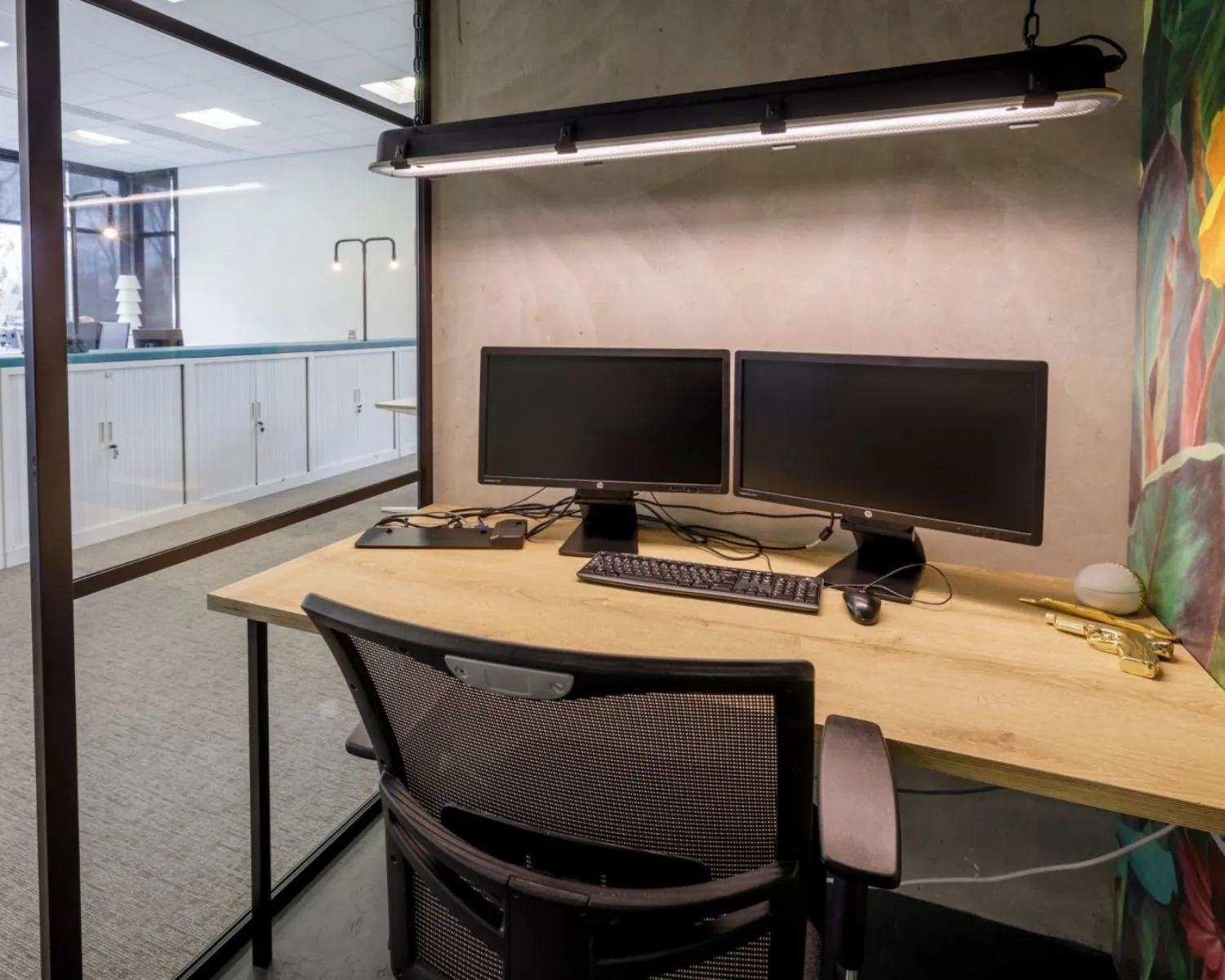 Moderne kantoorruimte met houten bureau, dubbele monitoren en glazen scheidingswand aan de Anderlechtstraat 15.