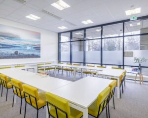 Moderne en lichte kantoorruimte aan de Anderlechtstraat 15 met witte tafels, gele stoelen en grote ramen.