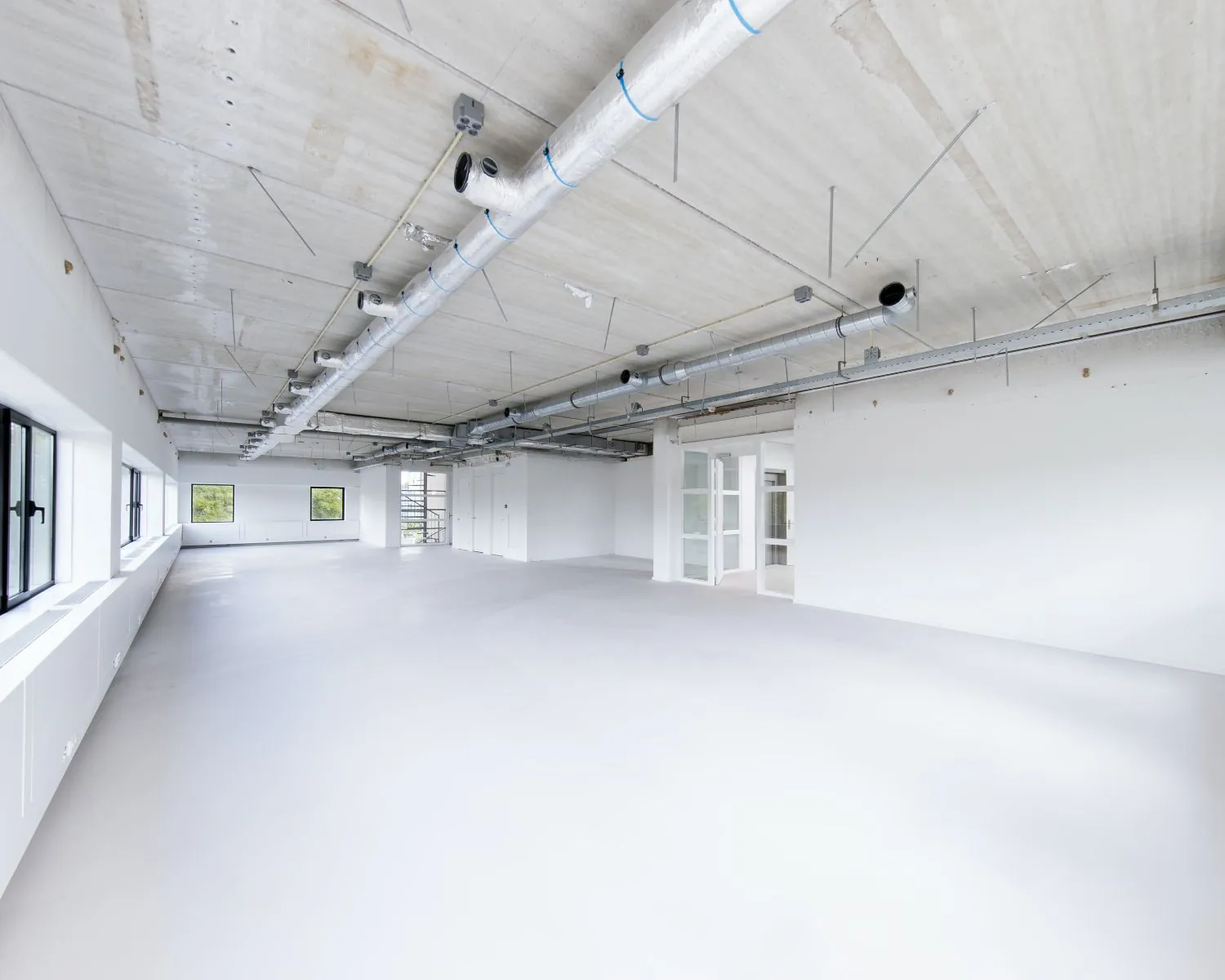 Lichte, lege kantoorruimte met grote ramen en industriële plafondafwerking aan de Basicweg 12 in Amersfoort.