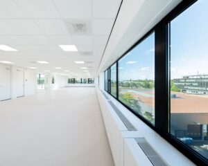 Lichte, moderne kantoorruimte te huur aan de Basicweg 12 in Amersfoort met grote ramen en uitzicht op een bedrijventerrein.