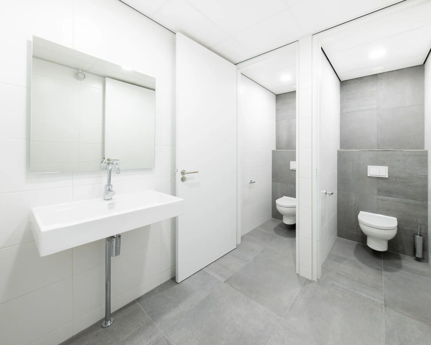 Moderne, gedeelde toiletruimte met twee toiletcabines en een wastafel in een kantoorpand aan de Basicweg 12 in Amersfoort.
