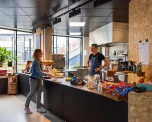 Modern ingerichte kantine in een kantoorruimte aan de Boerhaavelaan met een medewerker achter de balie en een klant die een bestelling plaatst.