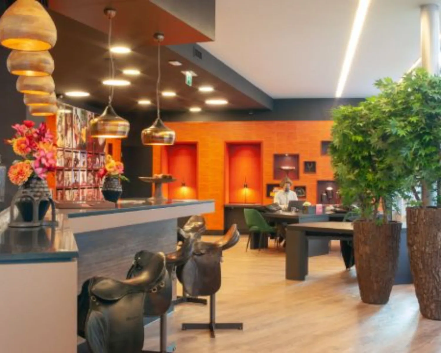 Moderne kantoorruimte aan de Claude Debussylaan 7 in Amsterdam met warme oranje accenten, een stijlvolle bar en groene planten.