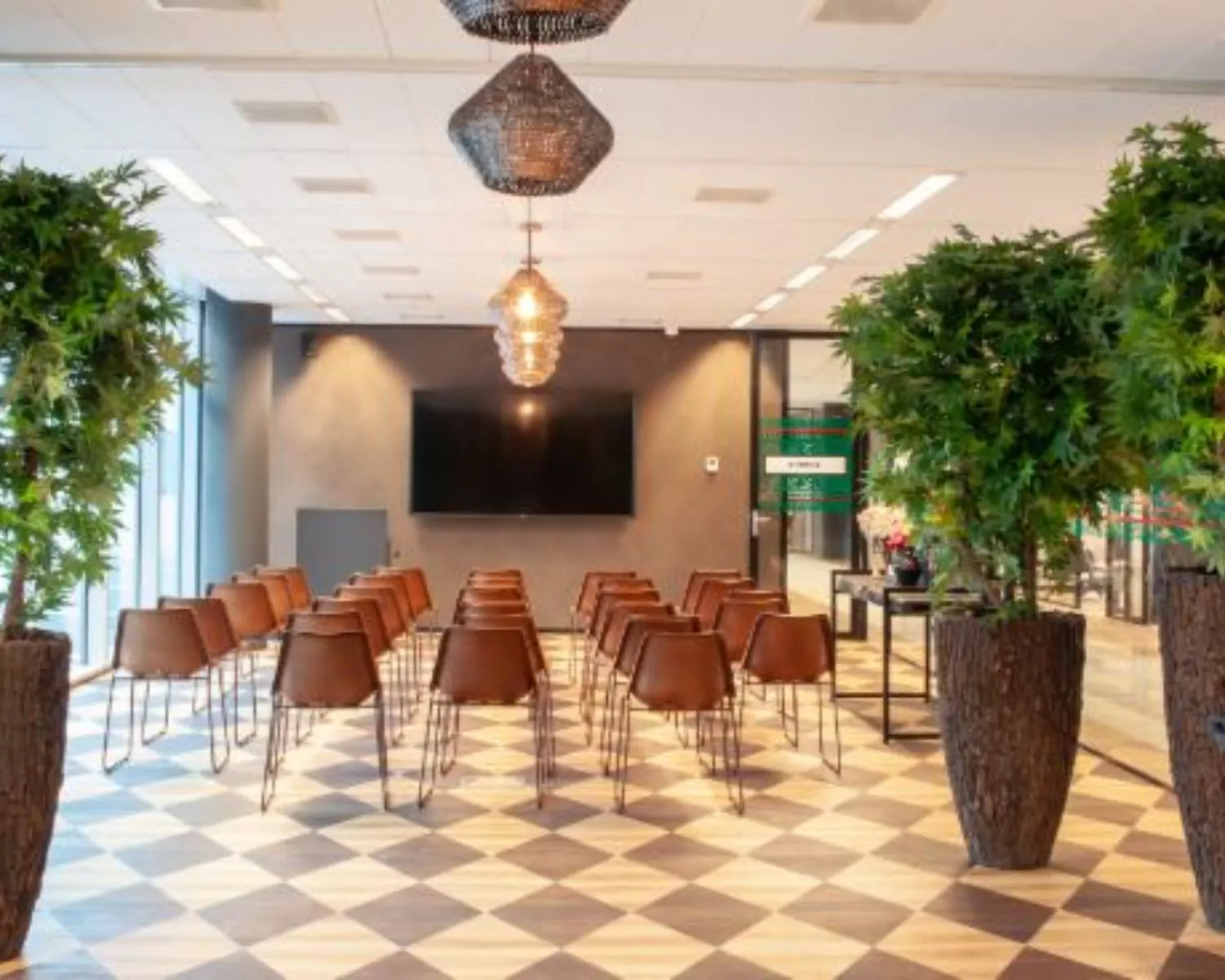Moderne vergaderruimte met leren stoelen, een flatscreen en grote planten aan de Claude Debussylaan 7 in Amsterdam.