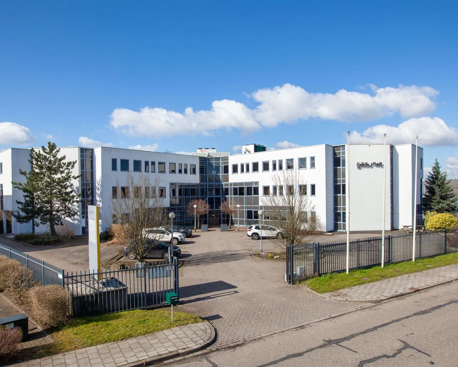 Modern wit kantoorgebouw aan de Coenecoop 7 in Gouda met parkeerplaats en omheind terrein.