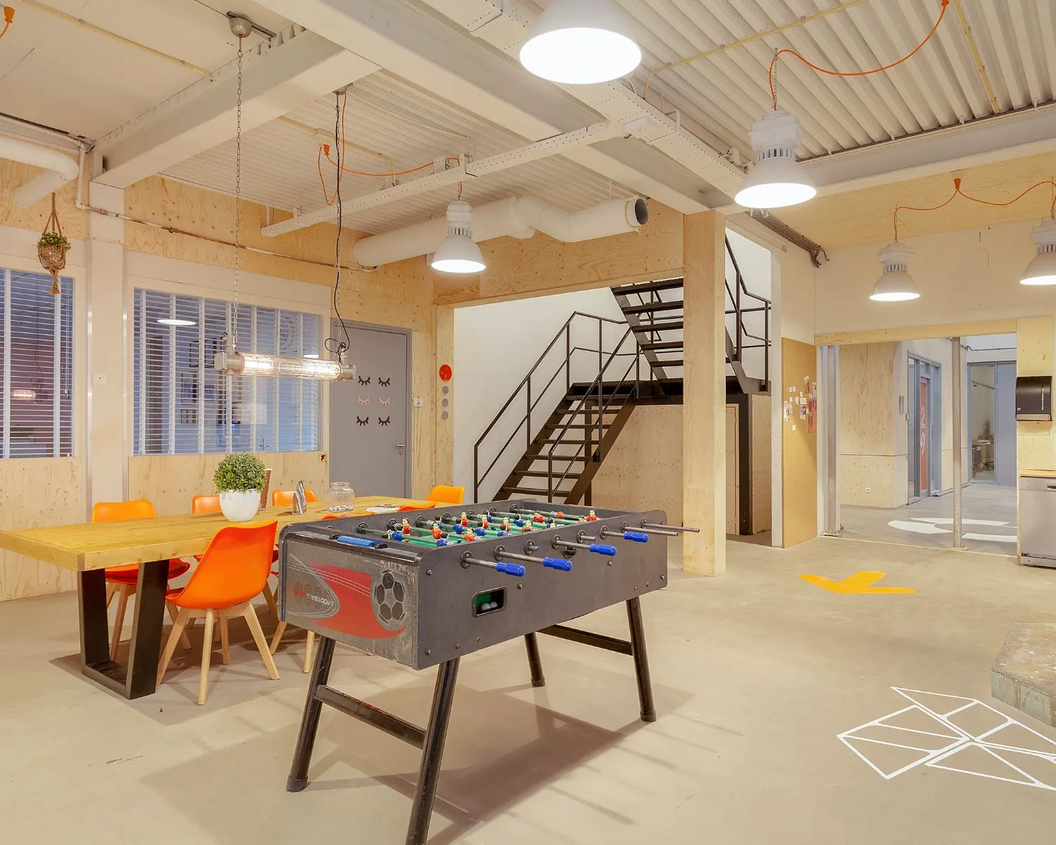 Moderne kantoorruimte in Rotterdam met een tafelvoetbaltafel, vergadertafel en industriële inrichting.