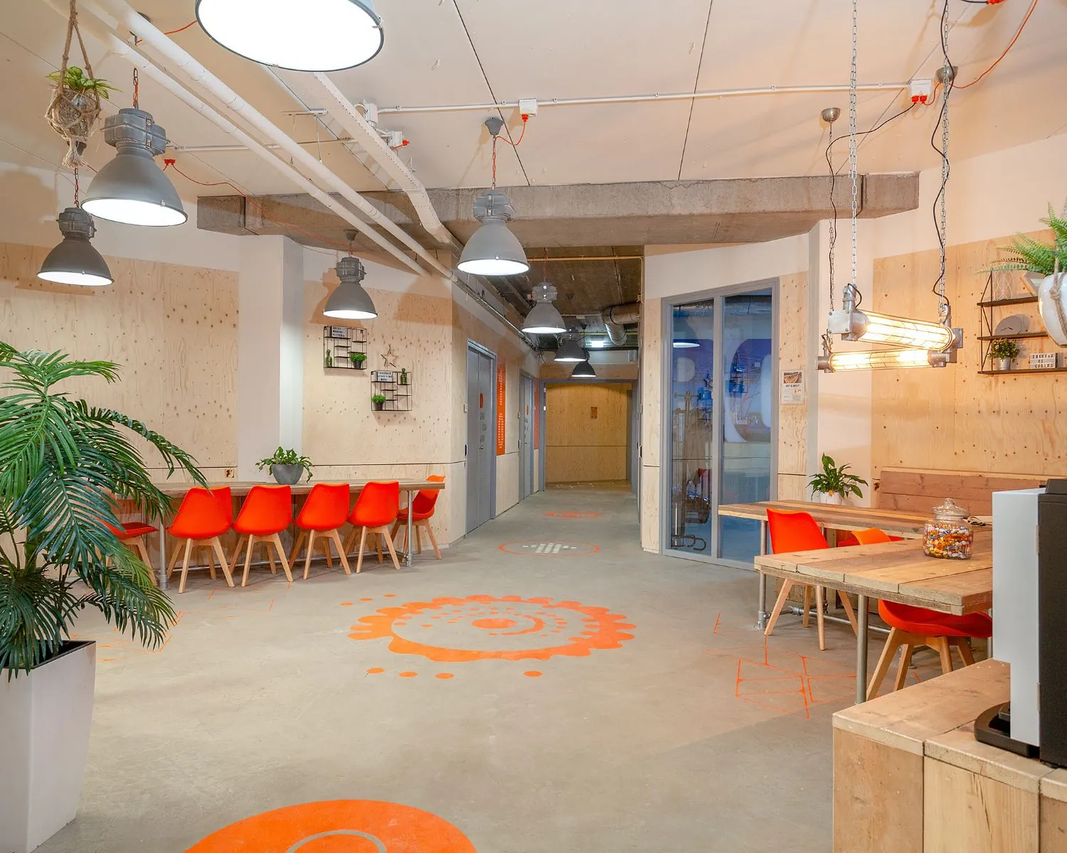 Moderne kantoorruimte met oranje stoelen, houten tafels en industriële verlichting aan de Corkstraat 46 in Rotterdam.