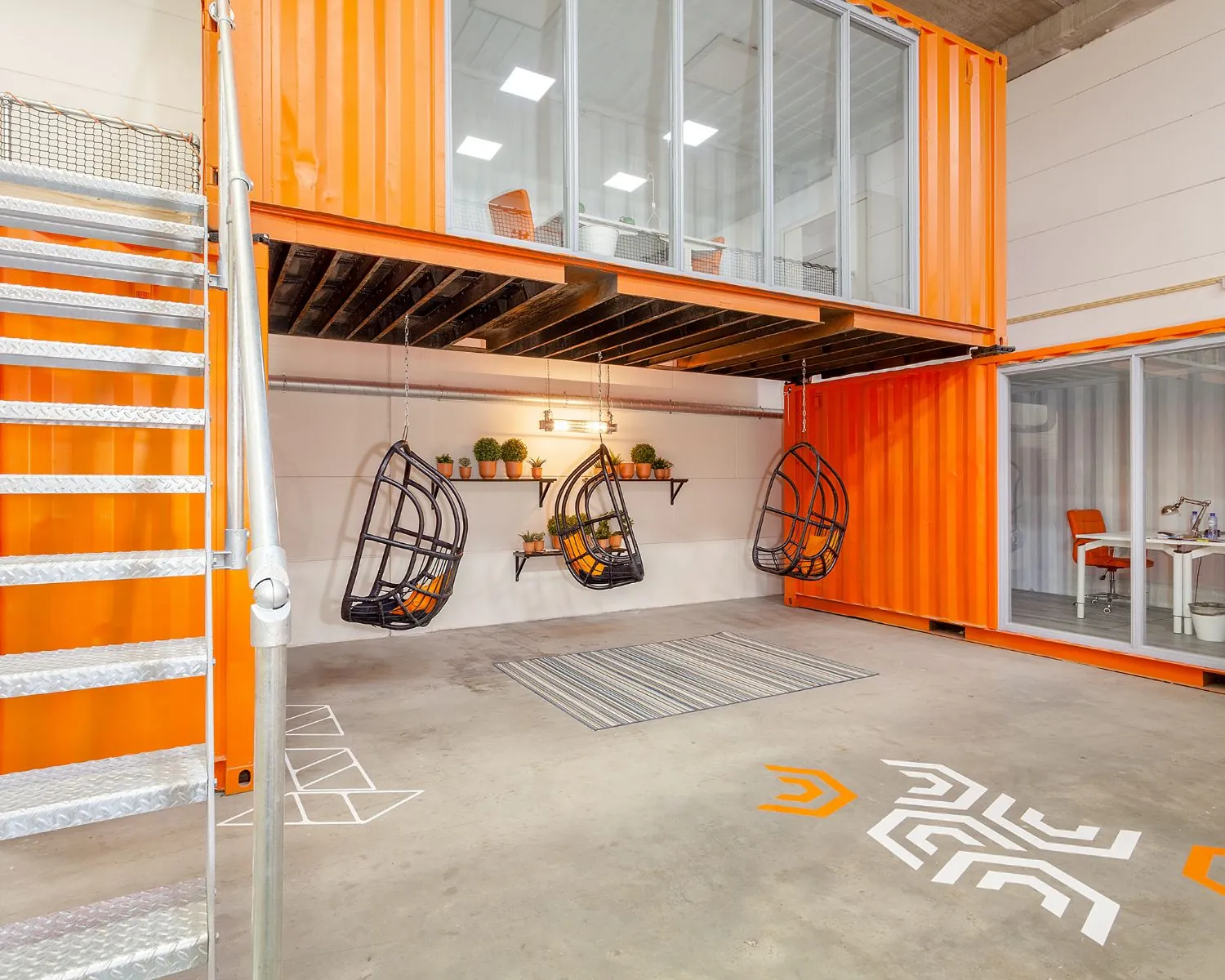 Moderne kantoorruimte in Rotterdam met oranje zeecontainers, hangstoelen en glazen kantoorunits.